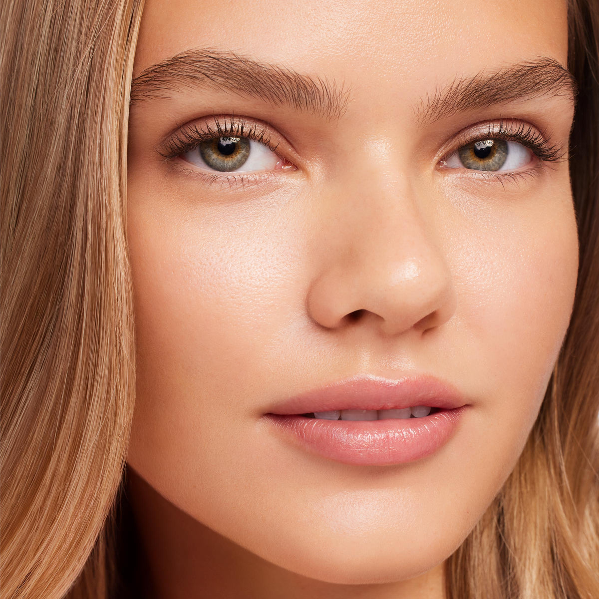 ColourPop Strawberry Lip Mask coating the model’s lips with a sheer, glossy pink sheen, shown in a tight face close-up under soft studio lighting to showcase smooth hydration and a supple finish.