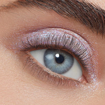 Ice Dream ColourPop Super Shock Shadow gleams on a close-up eyelid, delivering an icy lavender-pink, blue-shift shimmer across the lid and inner corner, highlighting natural lashes and brow for a sparkling, multidimensional finish.
