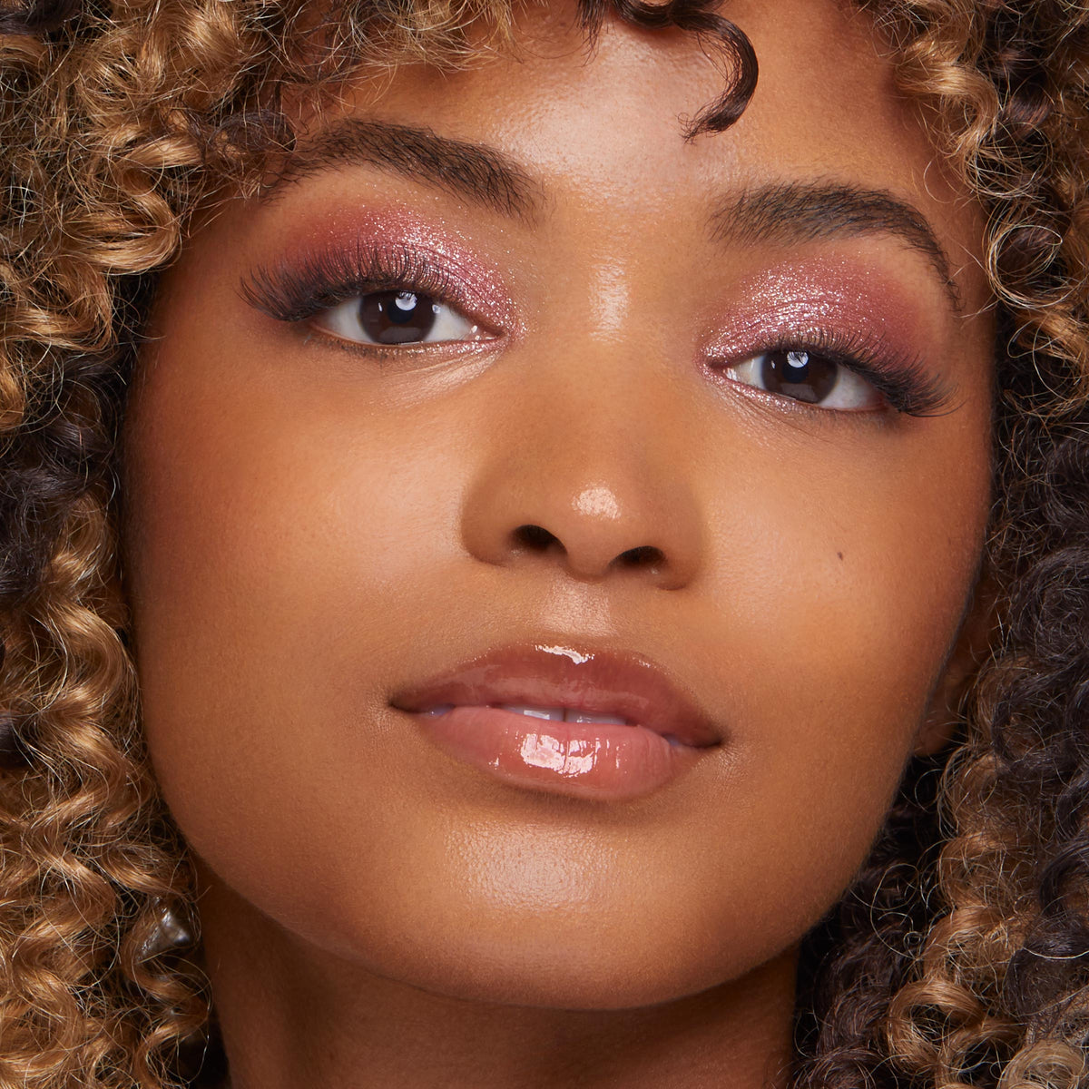 Shimmery pink eyeshadow illuminating a model’s lids, showcasing ColourPop Super Shock Shadow in Frog, with fluttery lashes and glossy nude lips in a tight close-up beauty look.
