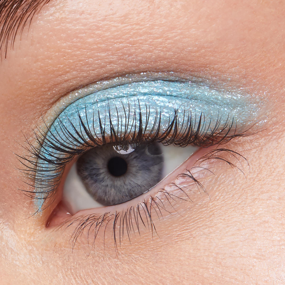 Shimmery aqua-blue eyeshadow sweeps across the eyelid, showcasing ColourPop Super Shock Shadow in Hydro Pump with a metallic, glittery finish and natural lashes, captured close-up to highlight the cool-toned, icy blue payoff.