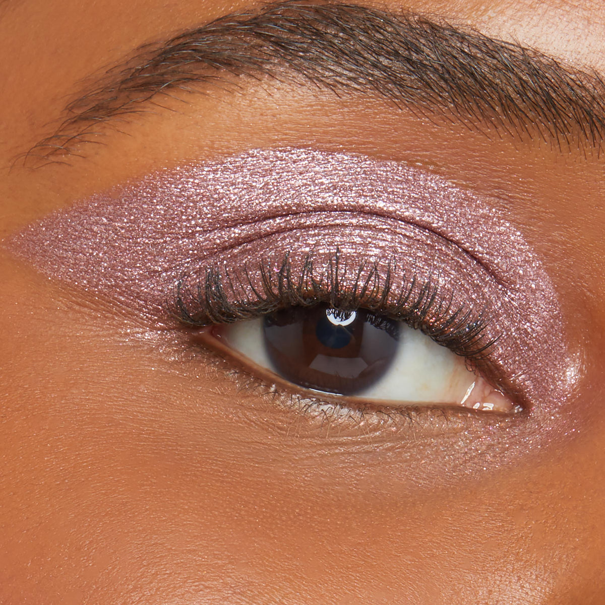 Close-up eyelid wears a shimmery metallic rose-mauve wing, showcasing ColourPop Shadow Stix in Next Spot; creamy stick shadow glides on smoothly with high-shine payoff and even coverage on brown skin for quick, long-wear eye looks.