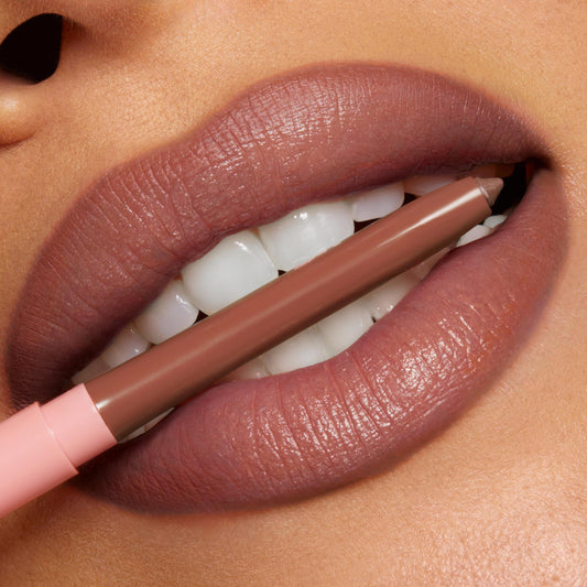ColourPop So Juicy Plumping Lip Liner with Peptides in Jaguar rests between full, defined lips, showcasing the brown‑nude shade and creamy pencil tip in a close-up beauty shot.