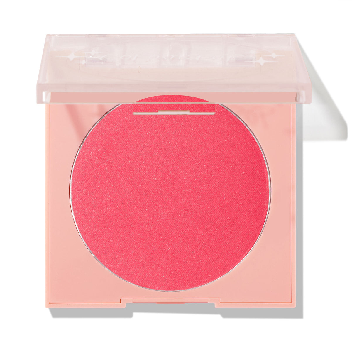 Staycation ColourPop Pressed Powder Blush displays a vivid coral-pink pan with the clear lid half open, set in a peach square compact on a white background, emphasizing the single-pan powder and sleek, travel-friendly packaging.