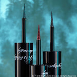 ColourPop Graphix Ink Liner, I Know What You Are, stands uncapped with an ultra-fine glitter brush tip displayed, flanked by two shimmer liners in black tubes with silver script against a teal, forest-blurred backdrop.