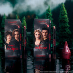 Just Bitten lip trio from the Twilight x ColourPop Eclipse collection standing upright in a dark forest setting, showing three vampy nude and berry lip pencils and sticks beside character-adorned boxes for dramatic, fandom-inspired makeup looks.