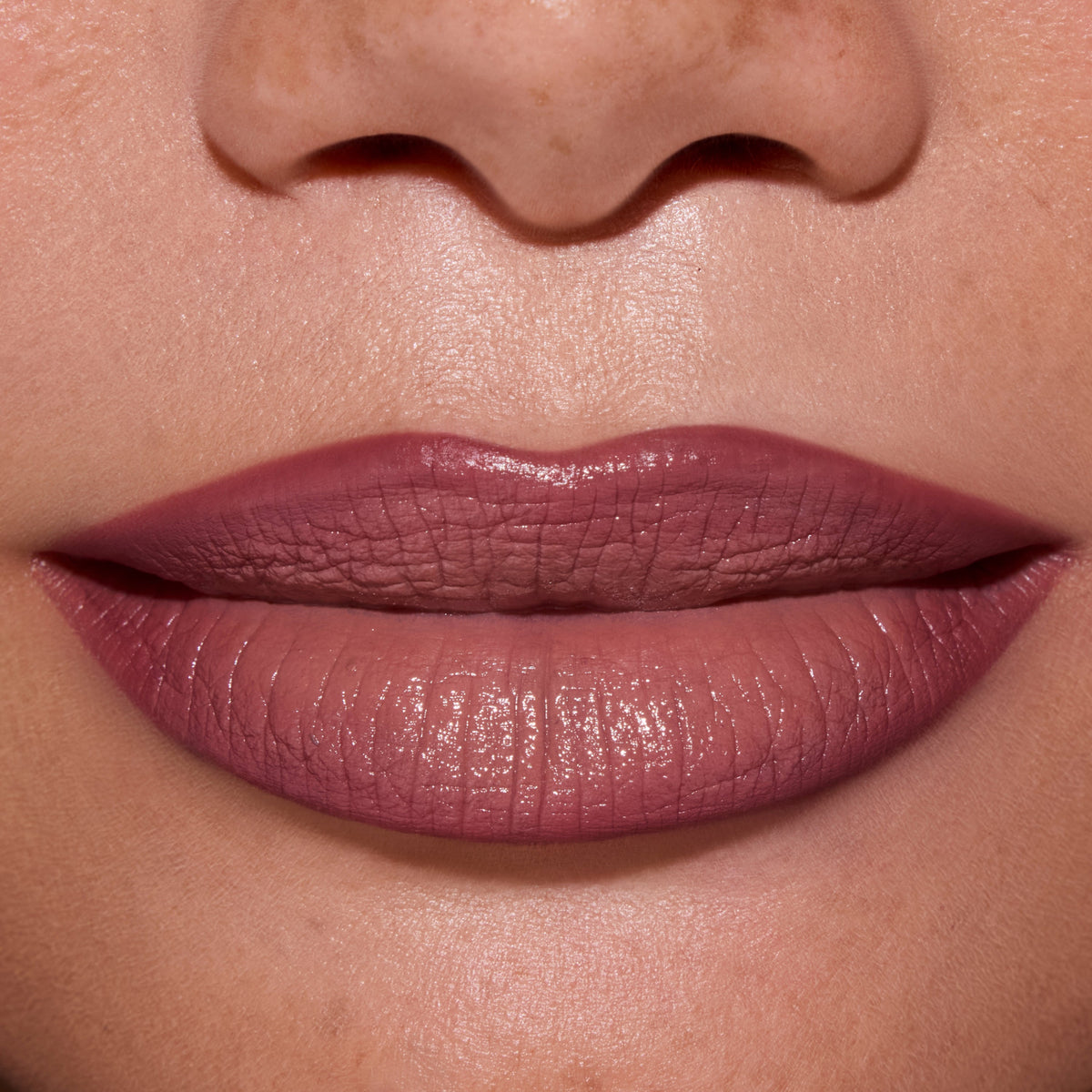 Close-up of full lips wearing ColourPop Opposites Attract Lippie Stix, showing a smooth, satin-matte mauve finish inspired by Twilight tones on medium skin, highlighting even coverage and creamy texture for everyday makeup looks.