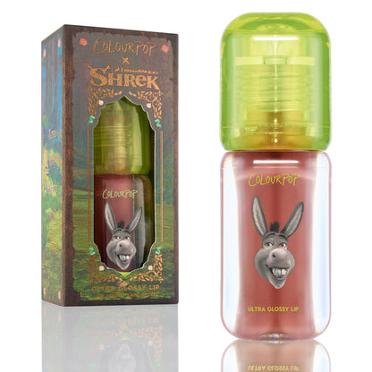 ColourPop Ultra Glossy Lip Noble Steed standing upright, showing mauve-pink gloss in a clear tube with neon green cap and Donkey graphic, positioned beside the ColourPop x DreamWorks Shrek forest-themed box.