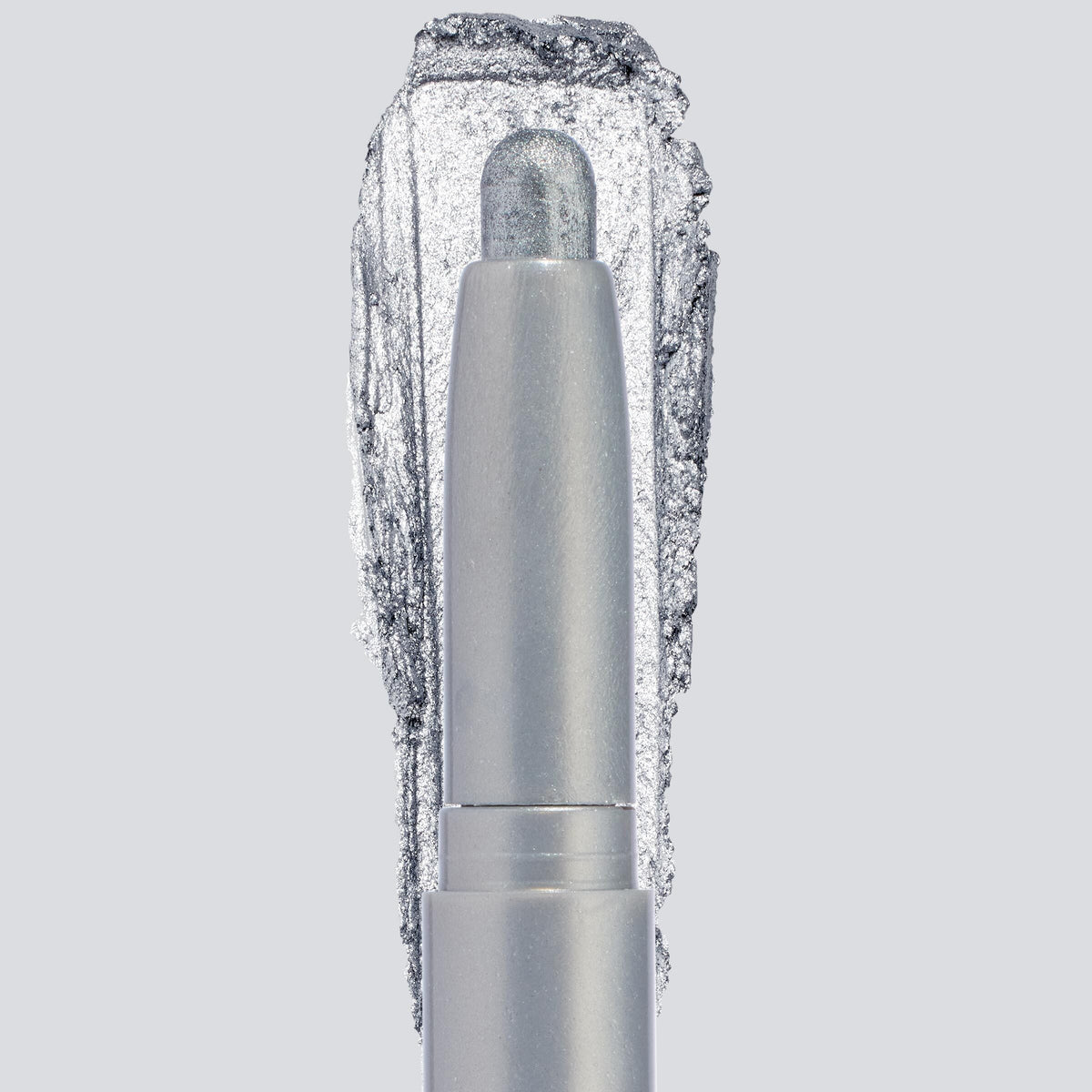 ColourPop Shadow Stix in Witch, Please showcases a creamy icy-silver shimmer, the crayon tip extended with a bold swatch behind to highlight pigment and sparkle, centered in a sleek silver tube on a light gray background.