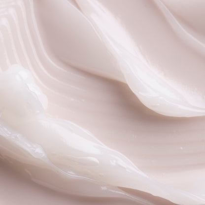 Coconut ColourPop Lip Mask swatched in thick, glossy white ribbons, showcasing a rich, cushiony texture and hydrating sheen on a smooth, pale pink surface.