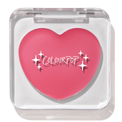 Heart-shaped bright rosy pink compact showcases the ColourPop Lip and Cheek Balm in Adore You, closed inside a clear square case with white logo and star accents, set against a clean white background.