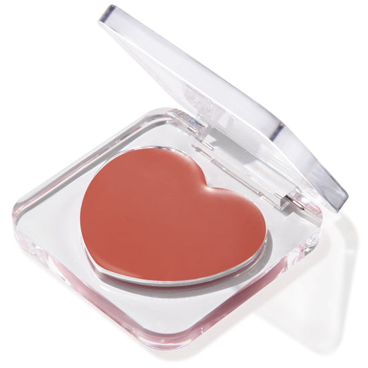 Heart-shaped Larchmont Village lip and cheek balm sits in a clear compact with the lid half open, revealing a warm rosy terracotta shade on a white background, ColourPop Lip and Cheek Balm for multiuse color.