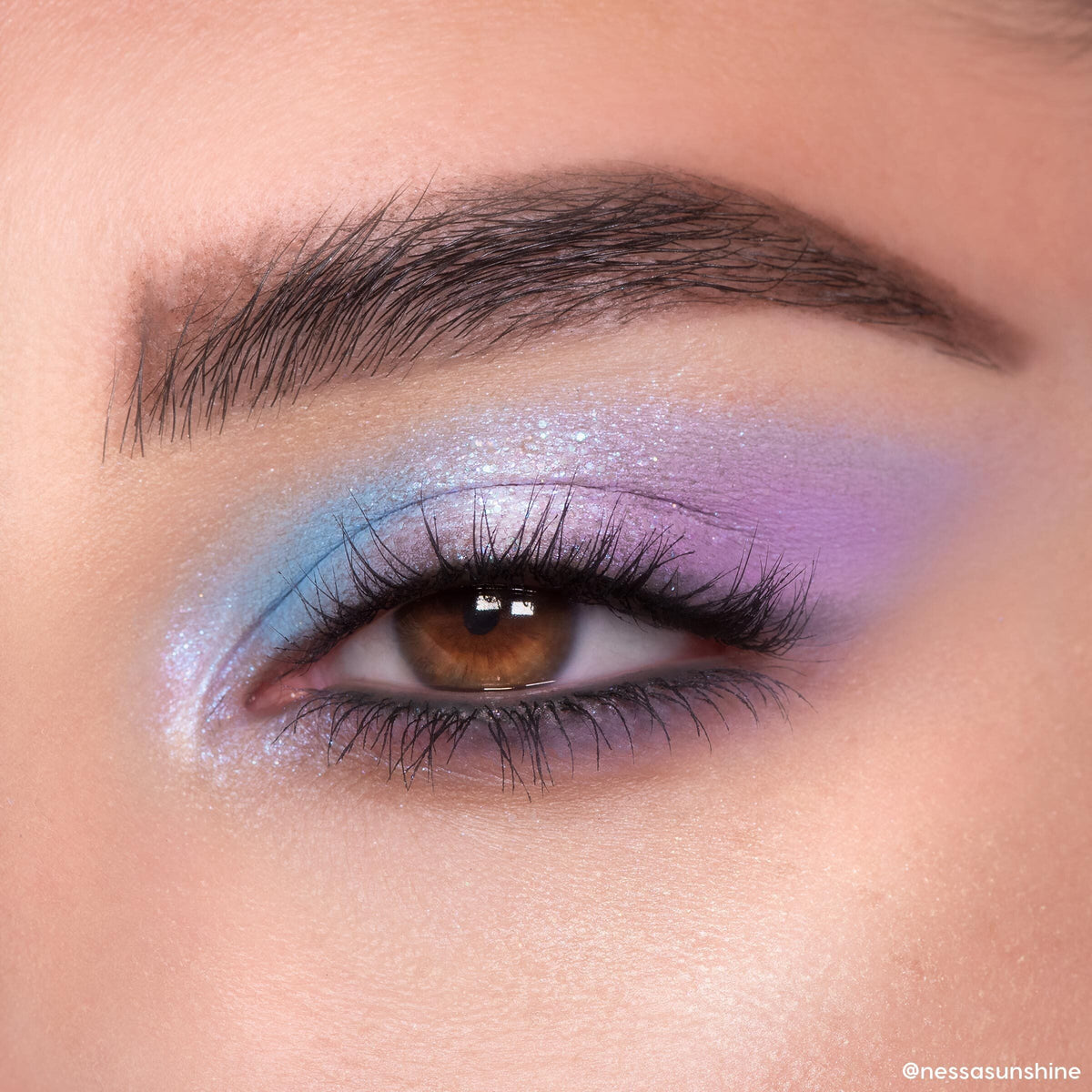 Pastel blue and lavender shimmer eyeshadow blends across a brown eye, showcasing the In A Trance ColourPop Shadow Palette with iridescent sparkle, tight-lined lashes, and a soft gradient finish in a close-up beauty look.