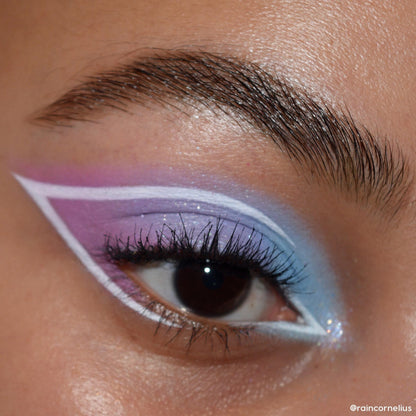 Pastel eye wearing a lavender-to-sky-blue gradient with crisp white graphic liner wings, showcasing the In A Trance shadow palette, a ColourPop Shadow Palette, in a close-up that highlights shimmer finish, defined lashes, and a groomed brow.